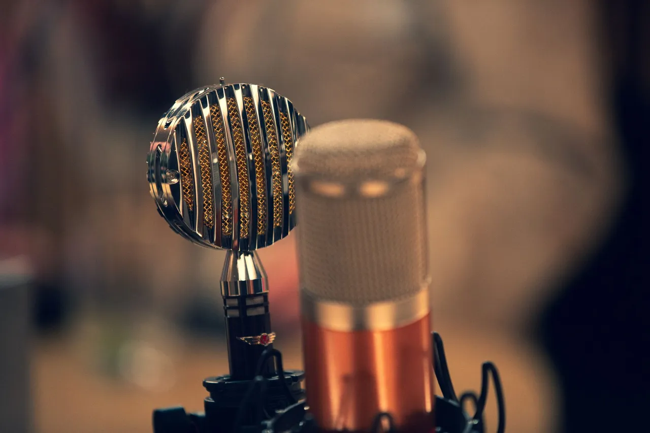 Close-up of a vintage and a modern microphone in a recording studio with a warm ambiance.