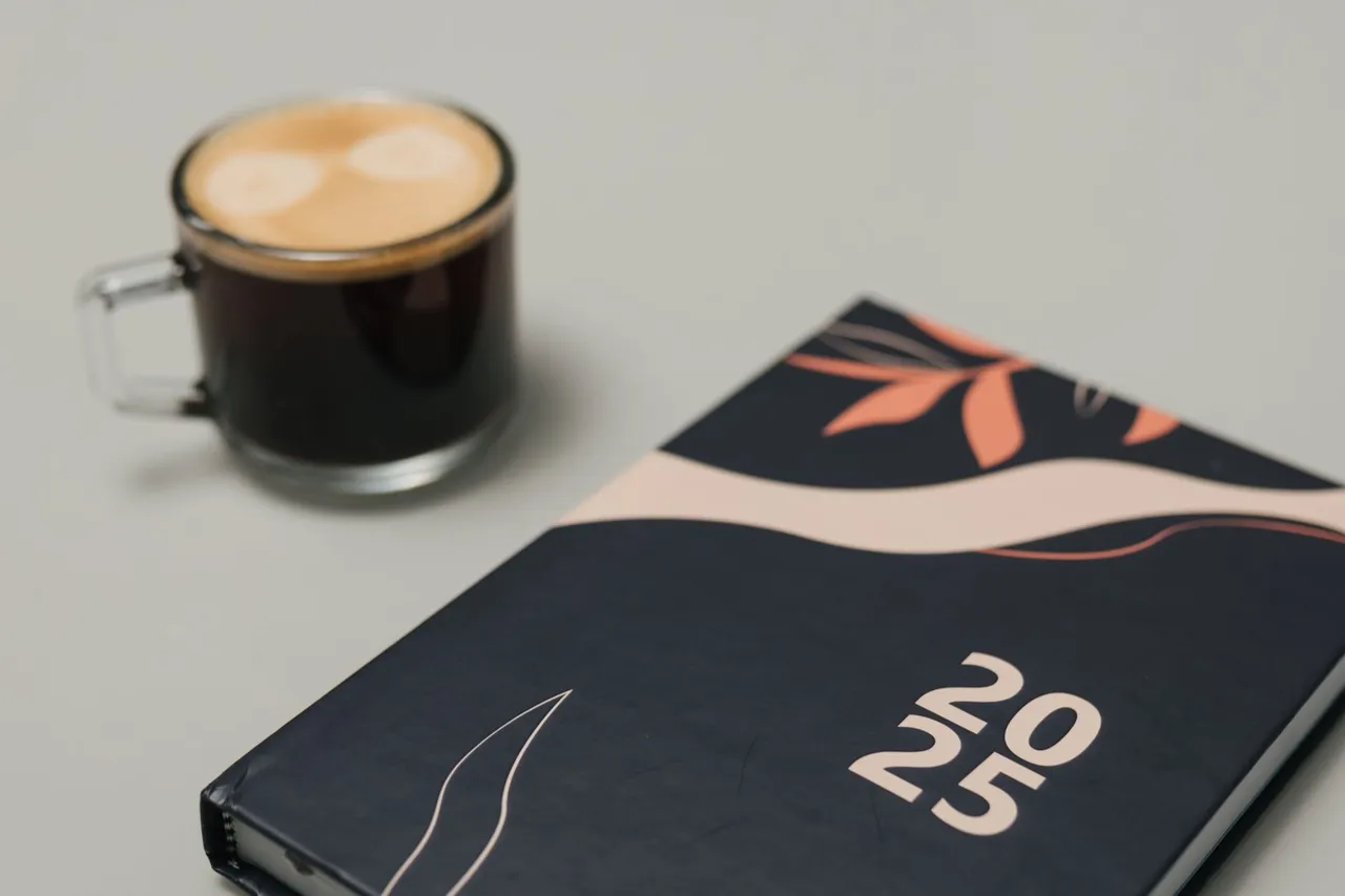 Stylish 2025 planner with a coffee mug on a neutral desk, perfect for planning sessions.