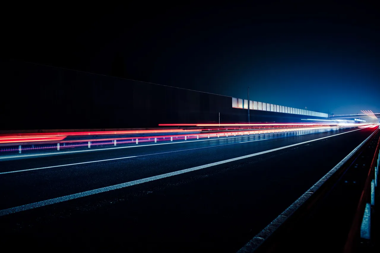 Vibrant long exposure photo capturing light streaks on a highway at night, illustrating speed and motion.