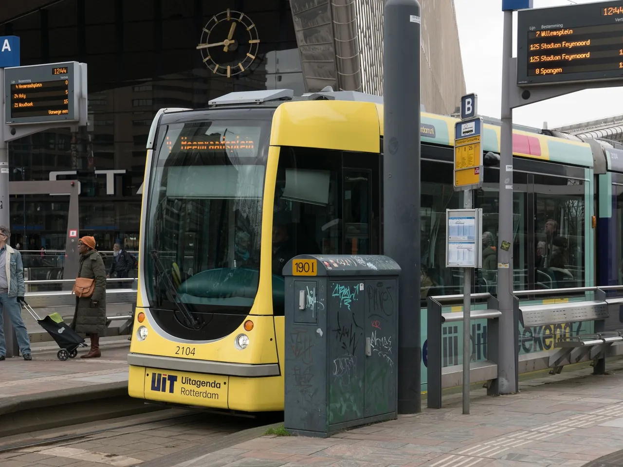 A vibrant tram at Rotterdam station square captures urban city life in motion.