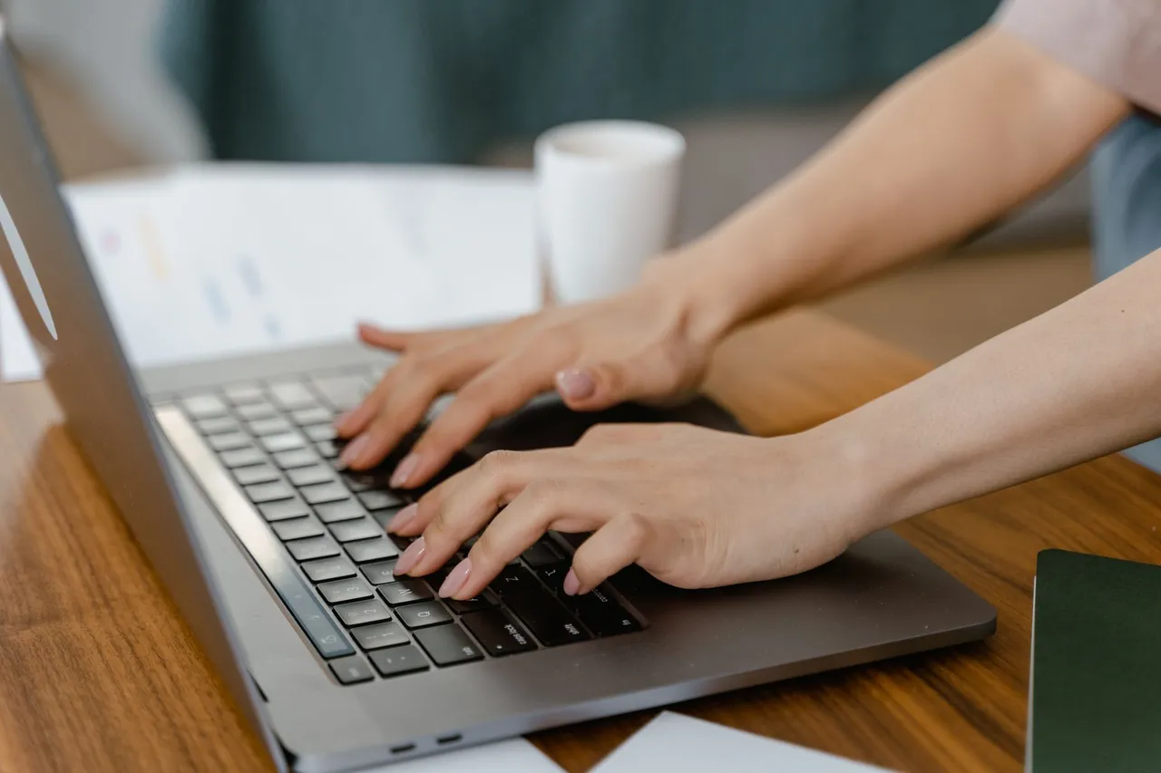 Close-up of a woman typing on a laptop in a cozy indoor setting, focusing on productivity.