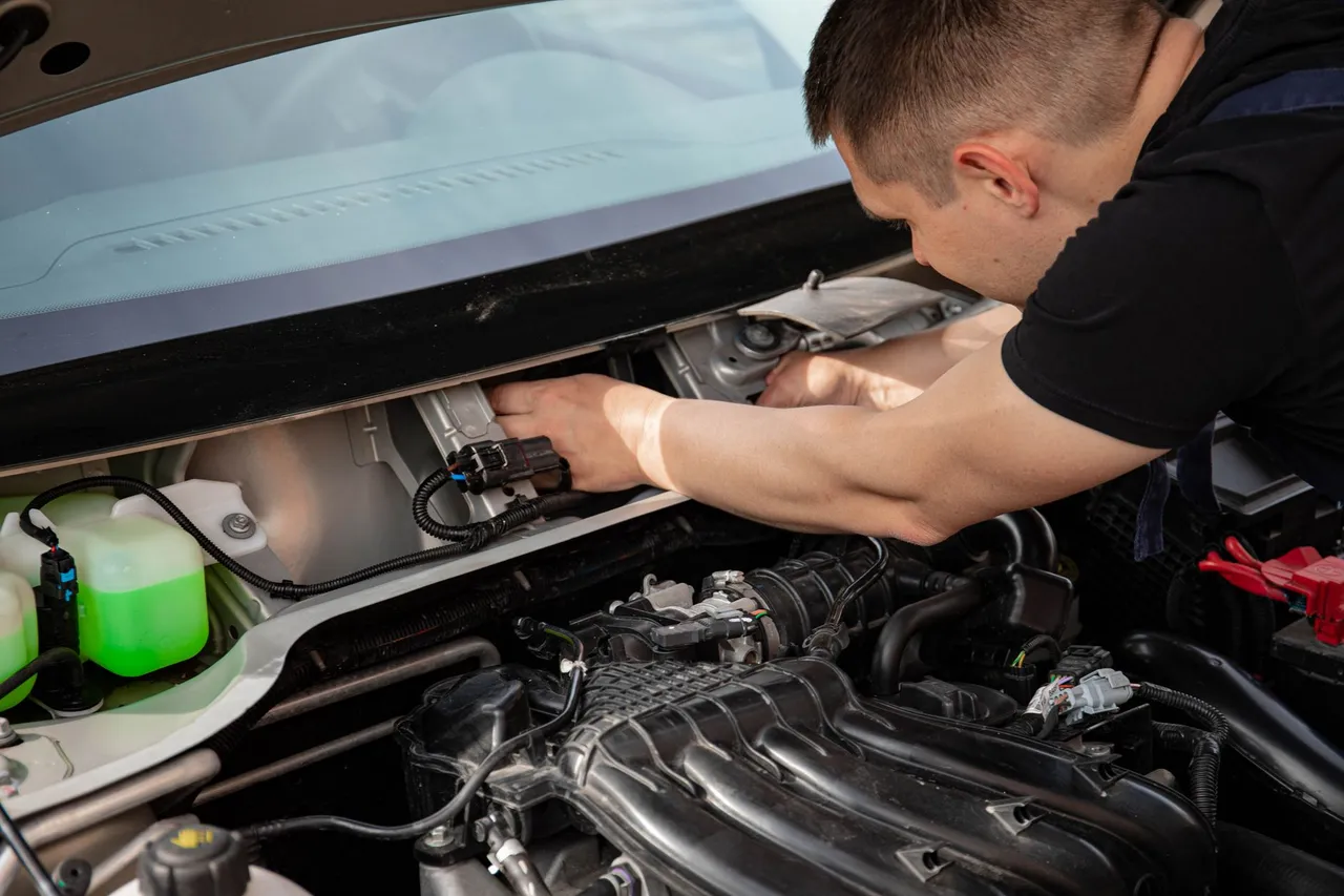 Mechanic focusing on car engine repair, showcasing skill and precision.