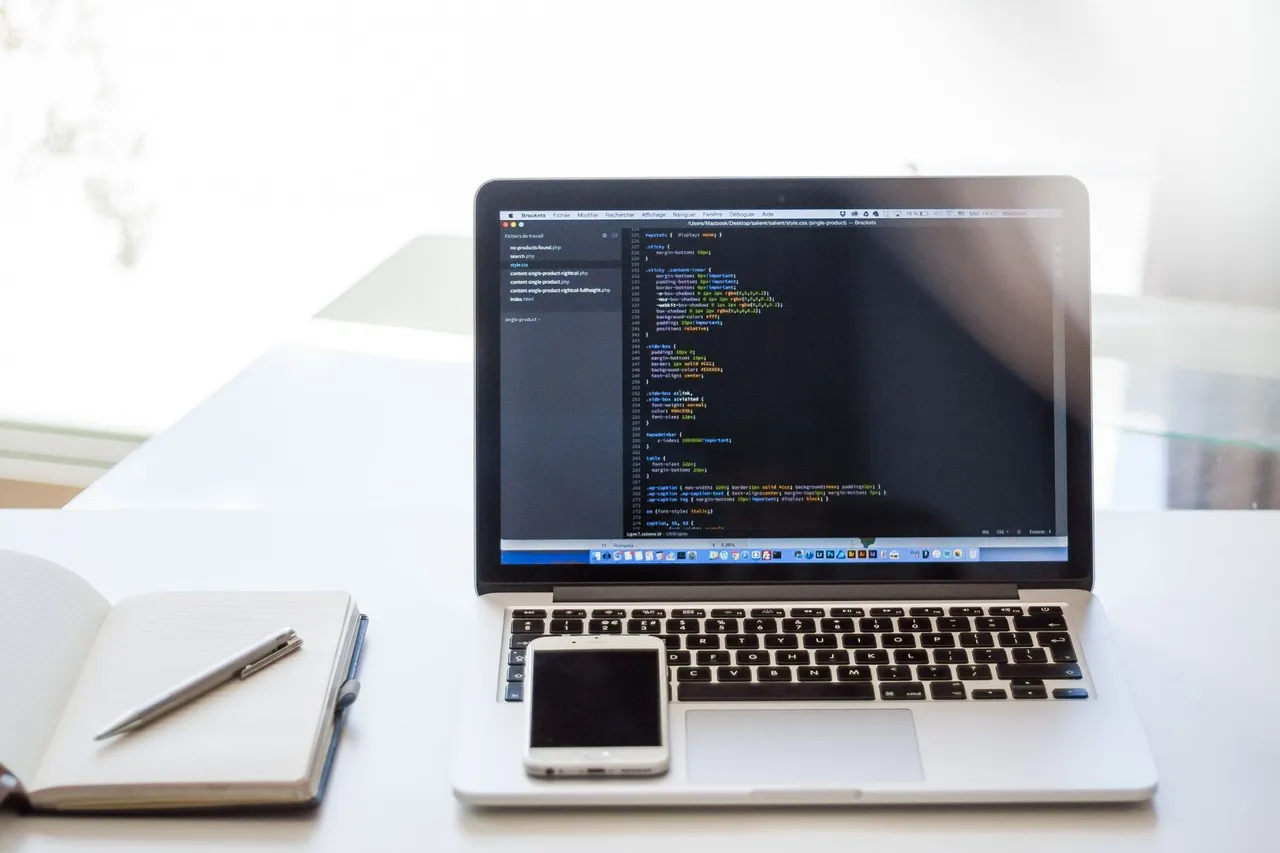 Open laptop displaying code on desk in bright, modern office setting. Ideal for tech and remote work context.