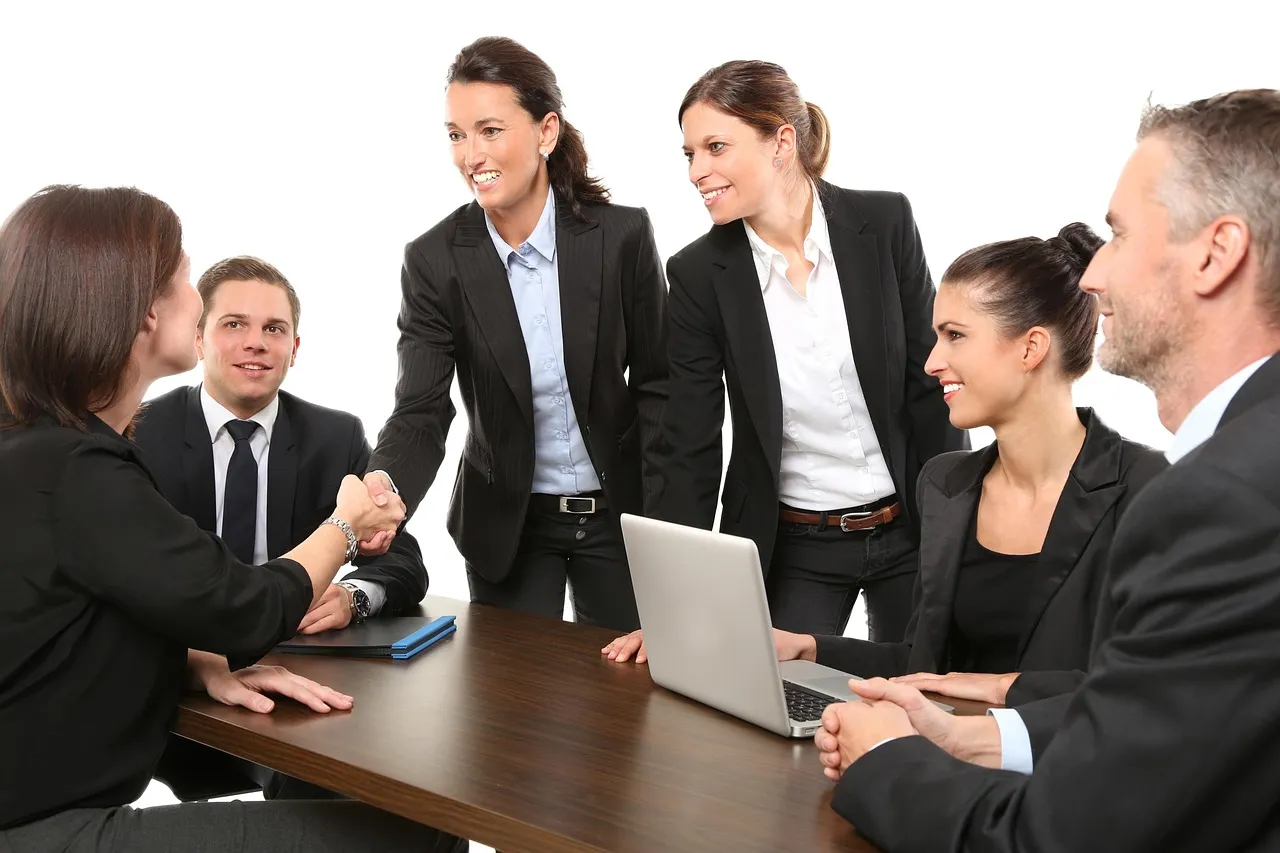 Three businessmen in suits collaborating in a modern office setting, focused on a laptop.